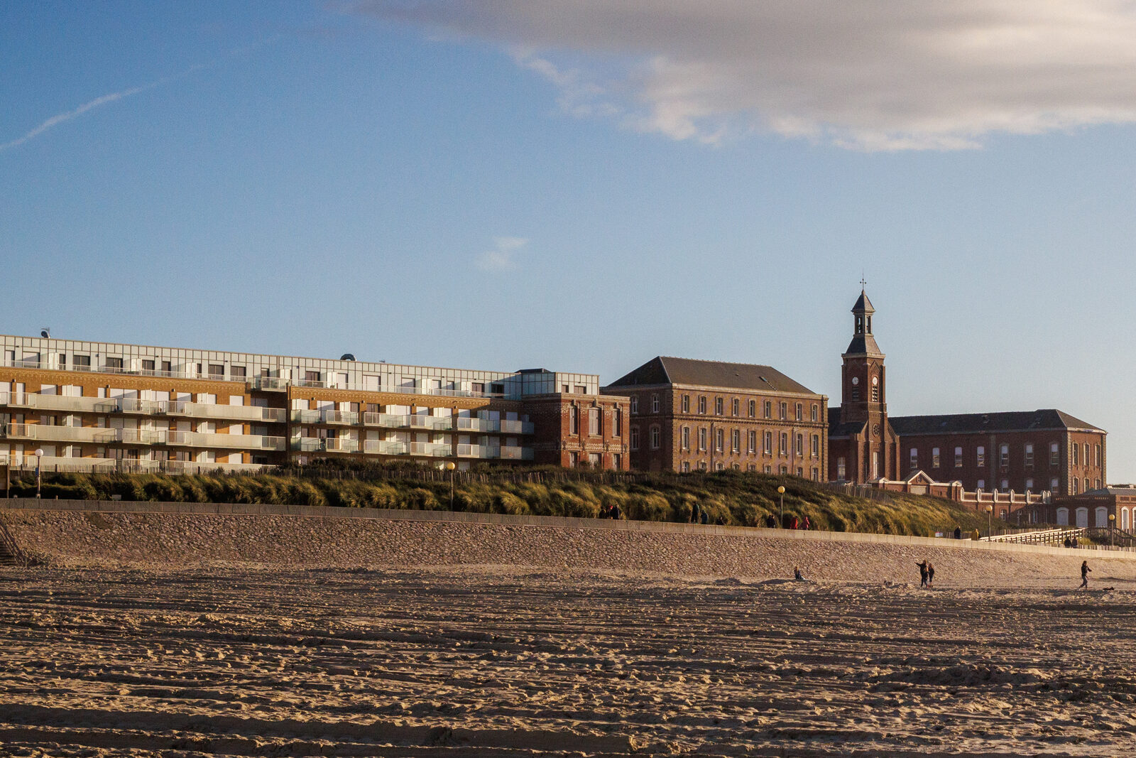 La plage de Berck-sur-Mer en fin d’après-midi, avec la digue-promenade, une résidence et les bâtiments en brique de l’hôpital maritime