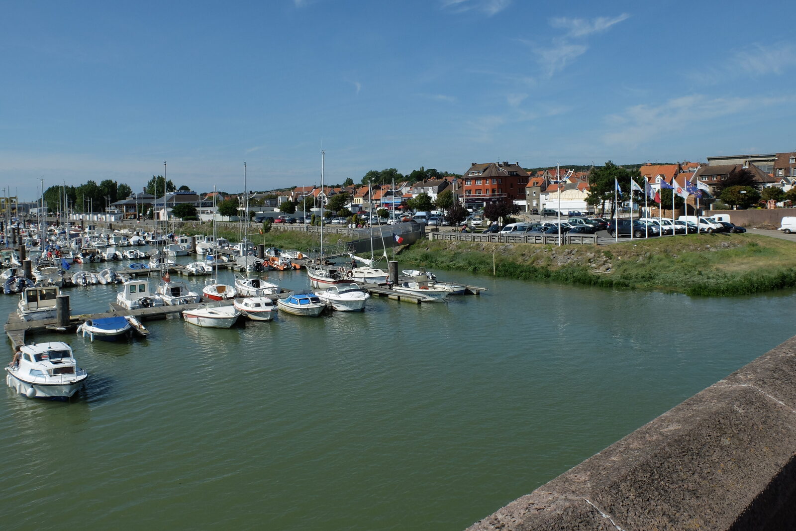 Le port de plaisance d’Étaples sur la Canche par temps ensoleillé, avec des bateaux amarrés aux pontons et les maisons de la ville en arrière-plan