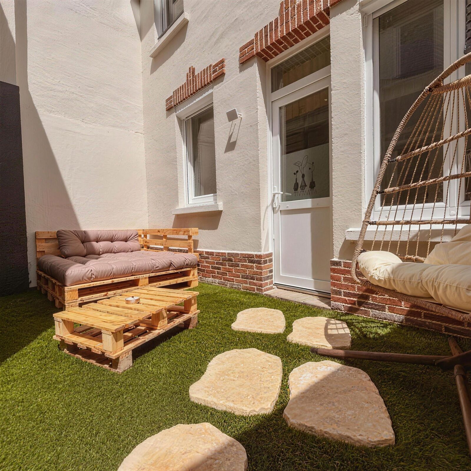 La cour privée : salon de jardin en palettes, pelouse et fauteuil suspendu